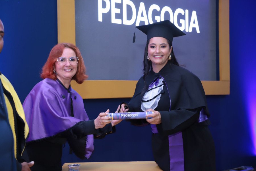 Gabriela Werneck recebendo de forma simbólica seu diploma pela coordenadora do curso, Miliana Sampaio